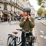 Cycliste attachant son casque gris près de son vélo, un homme casqué en trottinette sur la piste cyclable