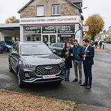 SUV Chery Tiggo 7 gris devant une concession Chery, un couple et un vendeur muni d'une tablette