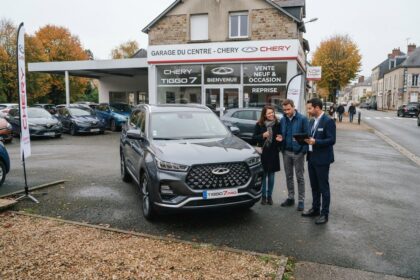 SUV Chery Tiggo 7 gris devant une concession Chery, un couple et un vendeur muni d'une tablette