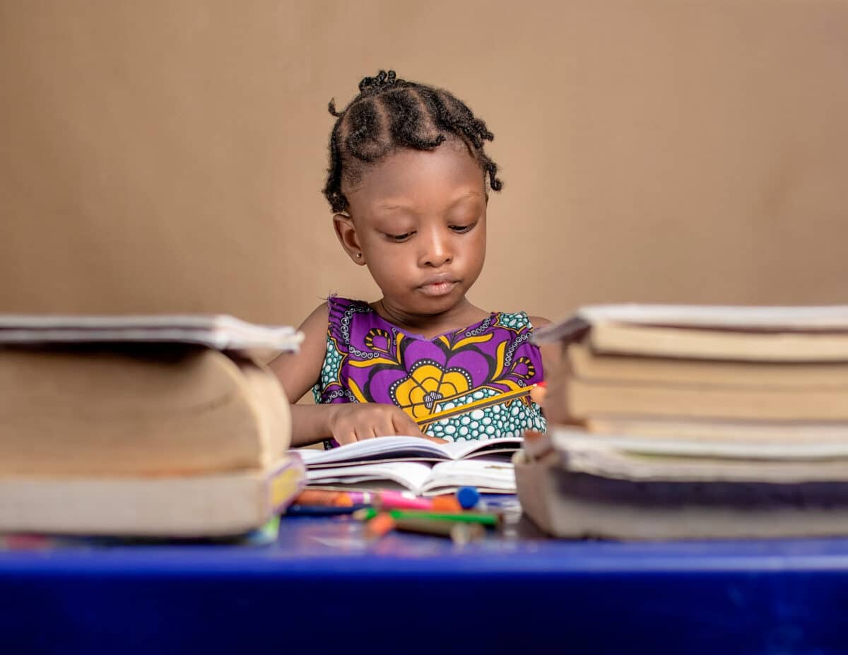 Jeune lectrice au regard sérieux, plongée au cœur de l'aventure des lettres Alphas, où chaque lettre prend vie pour la guider à travers les mystères de la lecture.