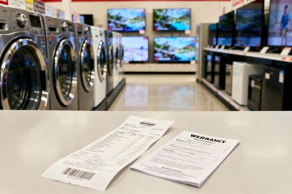 Rayon d’électroménager avec lave-linge et téléviseurs, un ticket de caisse et une notice de garantie posés au premier plan.