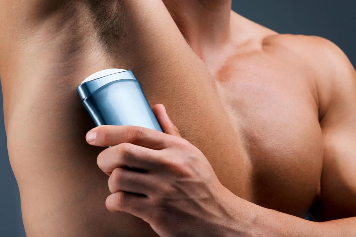 Un homme se préparant pour sa journée avec l'application essentielle d'un déodorant, garant d'une sensation de propreté et de protection contre les odeurs