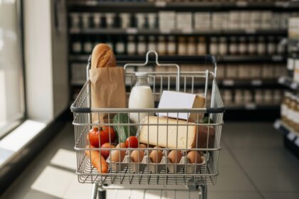 Caddie de supermarché à moitié rempli avec quelques produits essentiels.